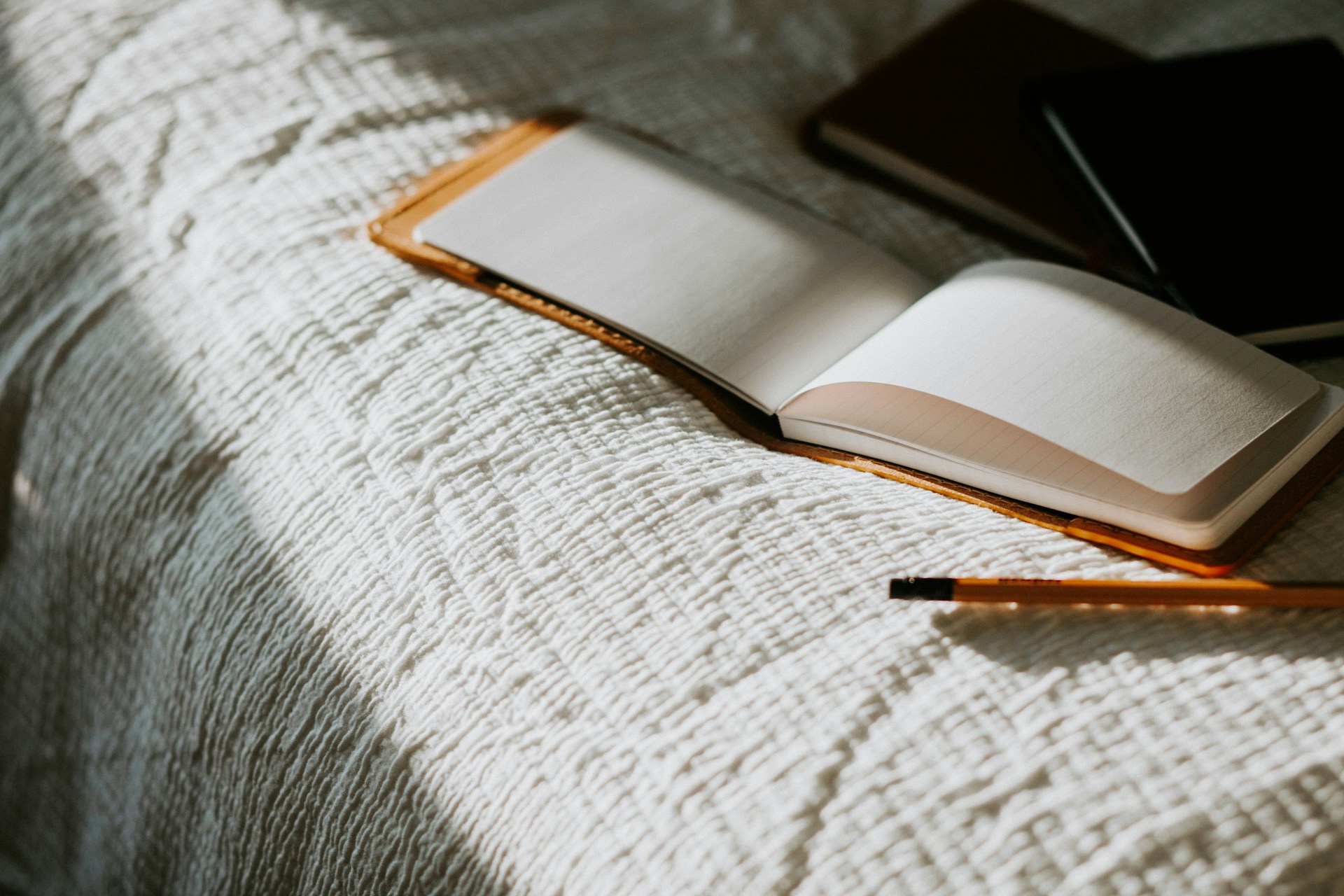 The Power of Journaling for Mental Clarity An open book sitting on top of a bed next to a pencil