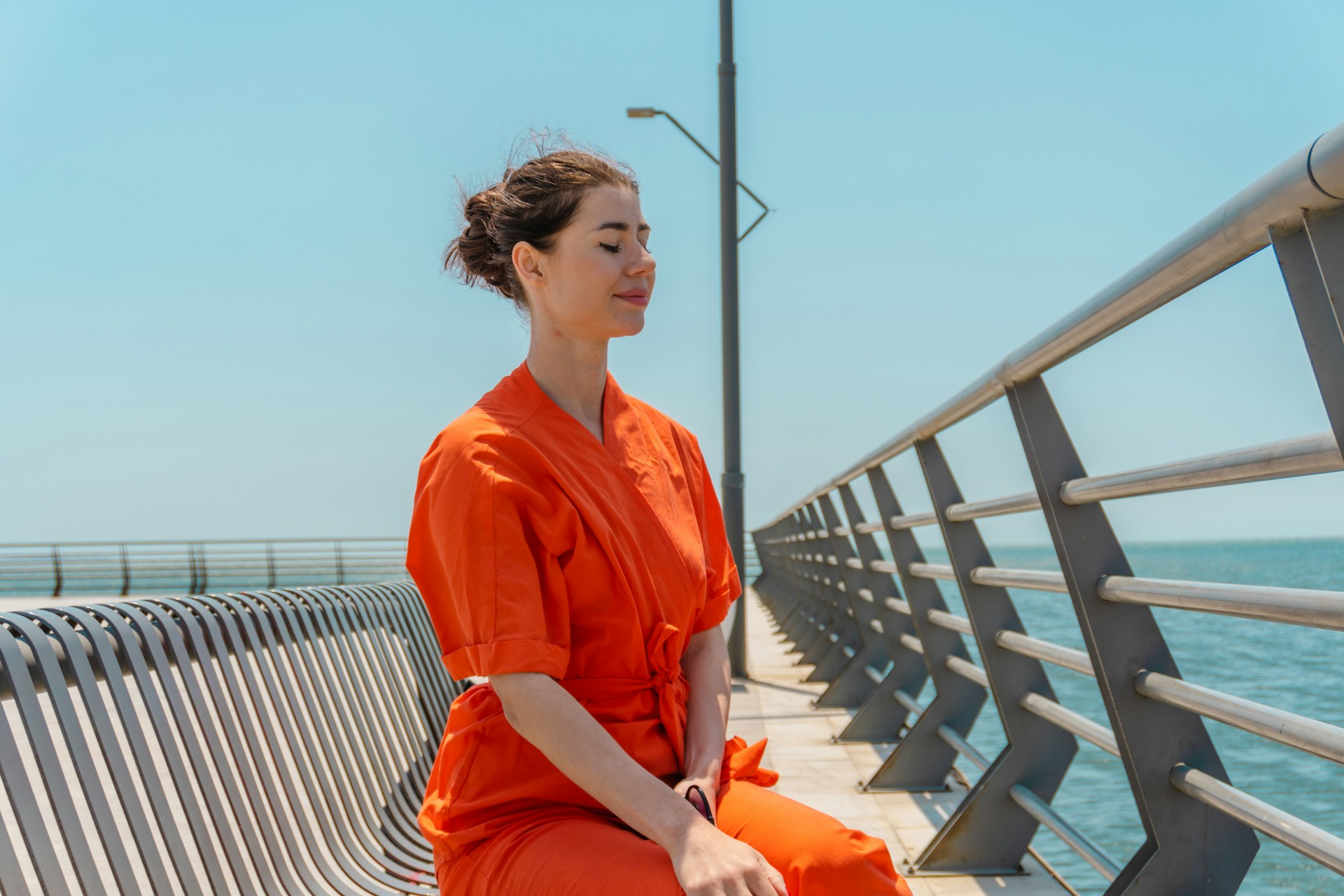 Simple Self-Care Practices to Recharge Your Day Woman in orange dress meditating by the ocean
