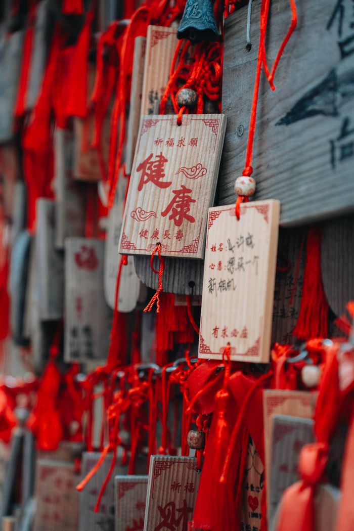 The Art of Drawing Readers In: Your attractive post title goes here Close-up of traditional Chinese wooden prayer tags with red ribbons, symbolizing wishes and blessings.
