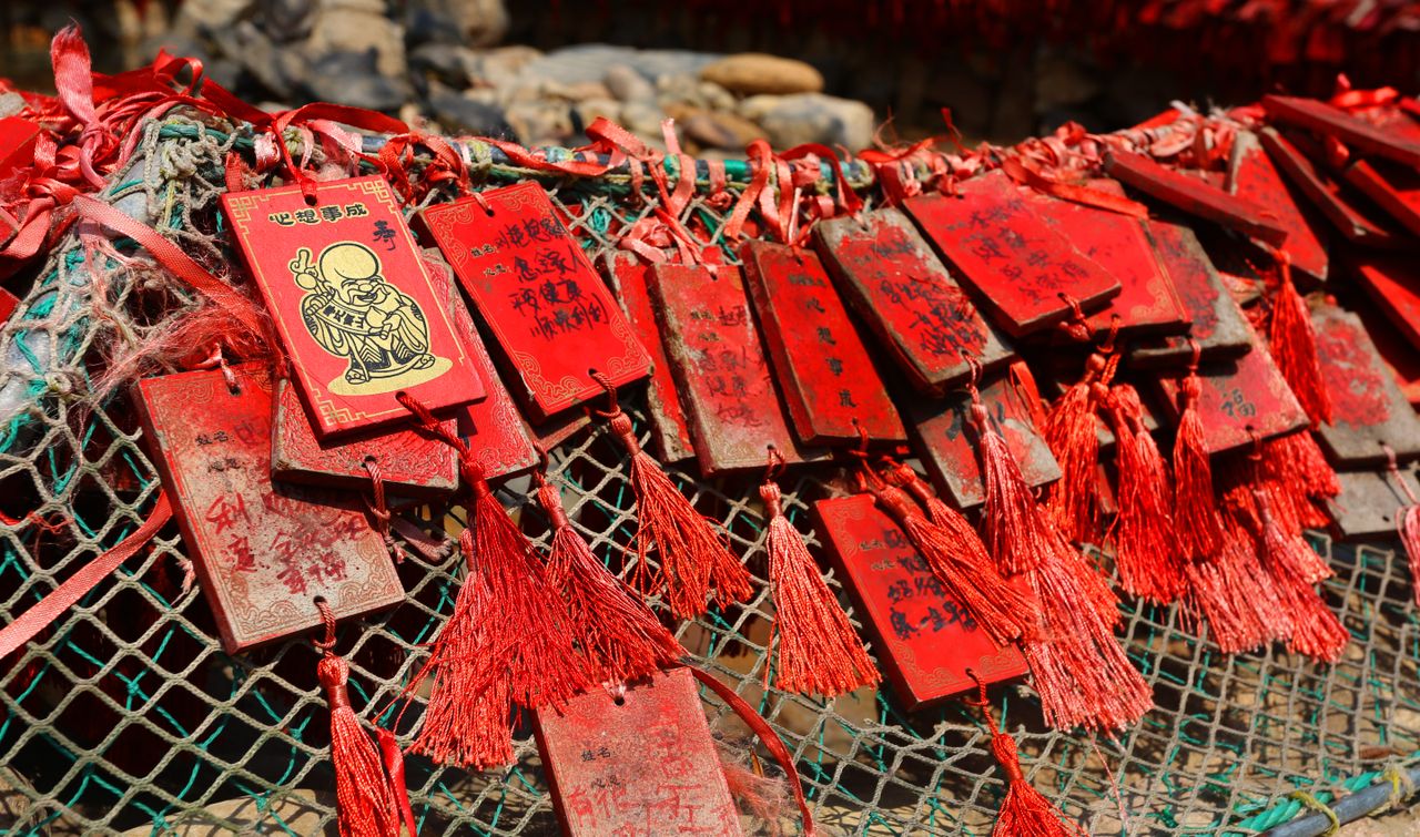 Close-up of red wooden prayer charms hanging outdoors, capturing the essence of Chinese cultural traditions.