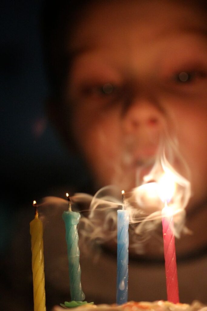 Mastering the First Impression: Your intriguing post title goes here A child blowing out four colorful birthday candles creating a soft, dreamy smoke effect.